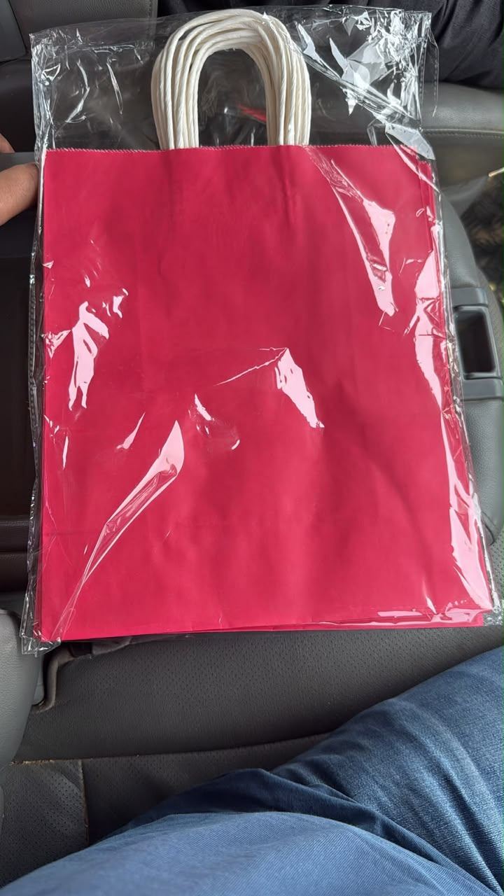 Échantillon de sac kraft teinté rose avec poignées blanches, sous film de protection avant livraison